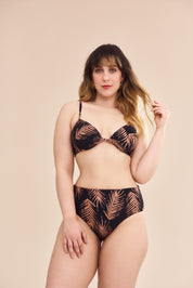 Modelo plus size vestindo conjunto de biquíni com estampa botânica em fundo preto, vista frontal.