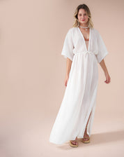 Vestido longo branco com mangas soltas e decote V, amarração abaixo do busto e fendas laterais, visto de frente.