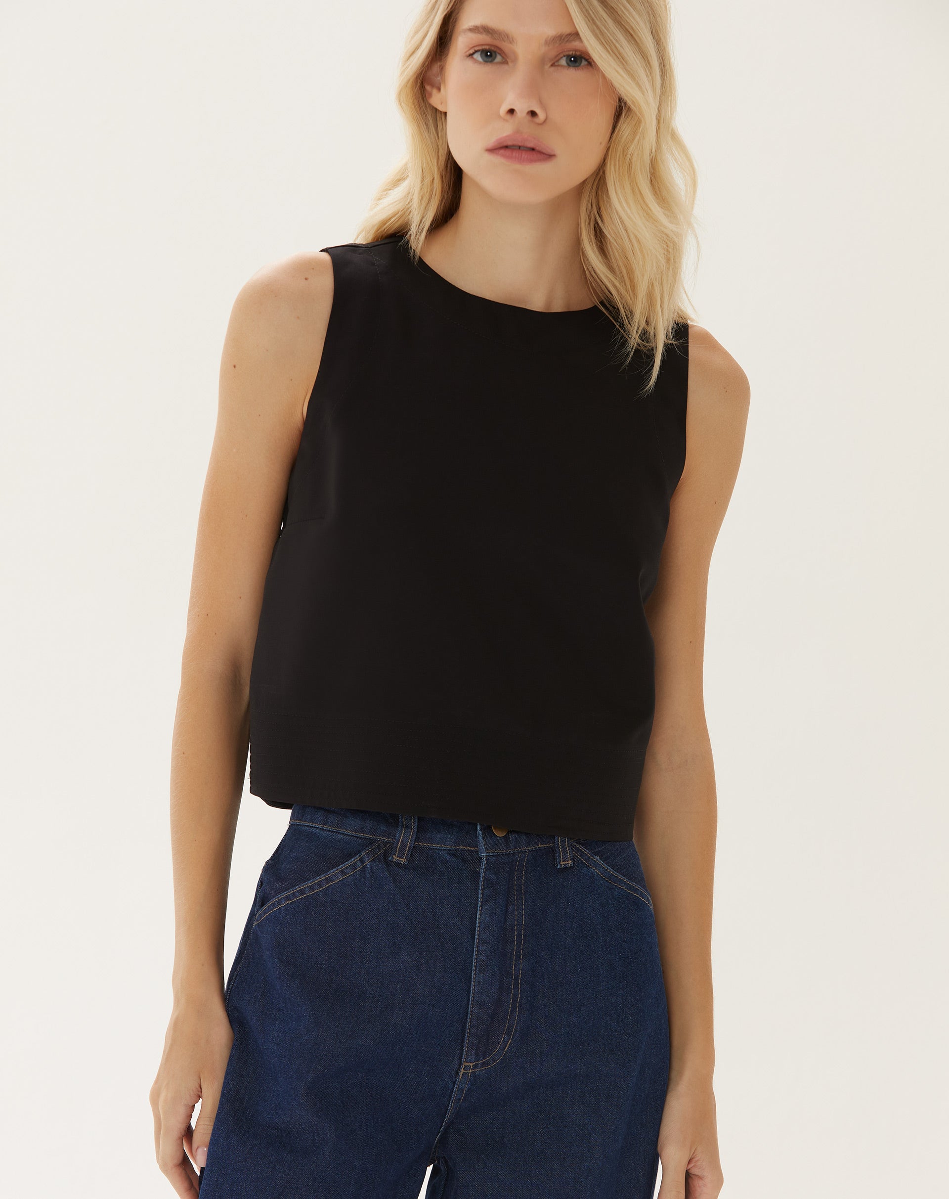 Modelo vestindo top cropped preto com calça jeans de cintura alta.