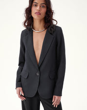 Blazer preto com lapela entalhada e manga longa, estilo alfaiataria.