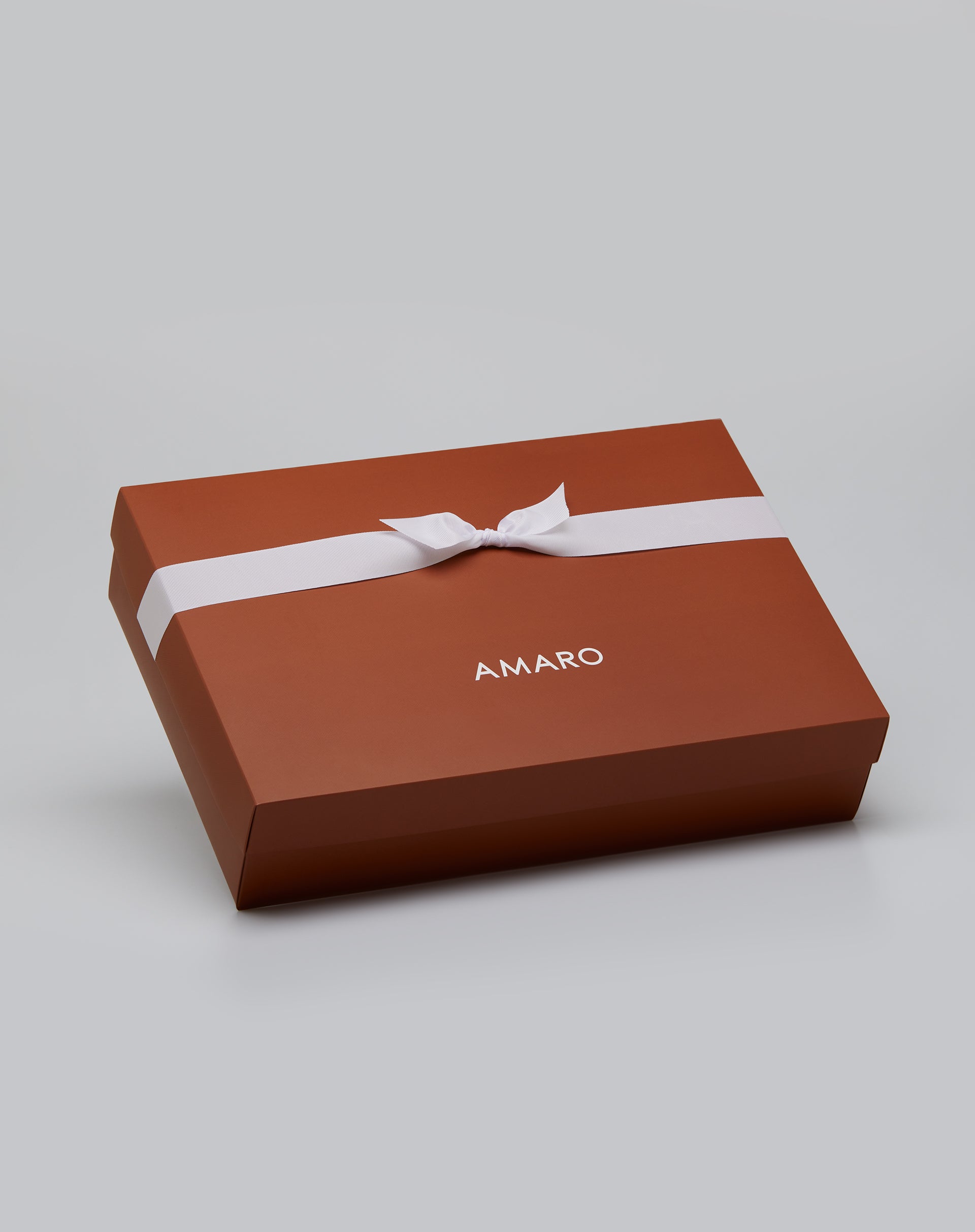 Embalagem de presente AMARO tamanho M na cor terracota com laço branco.