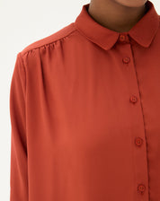 Close-up do colarinho pontudo da camisa marrom.