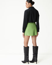 Vista traseira do shorts verde com vincos, combinado com camisa preta.