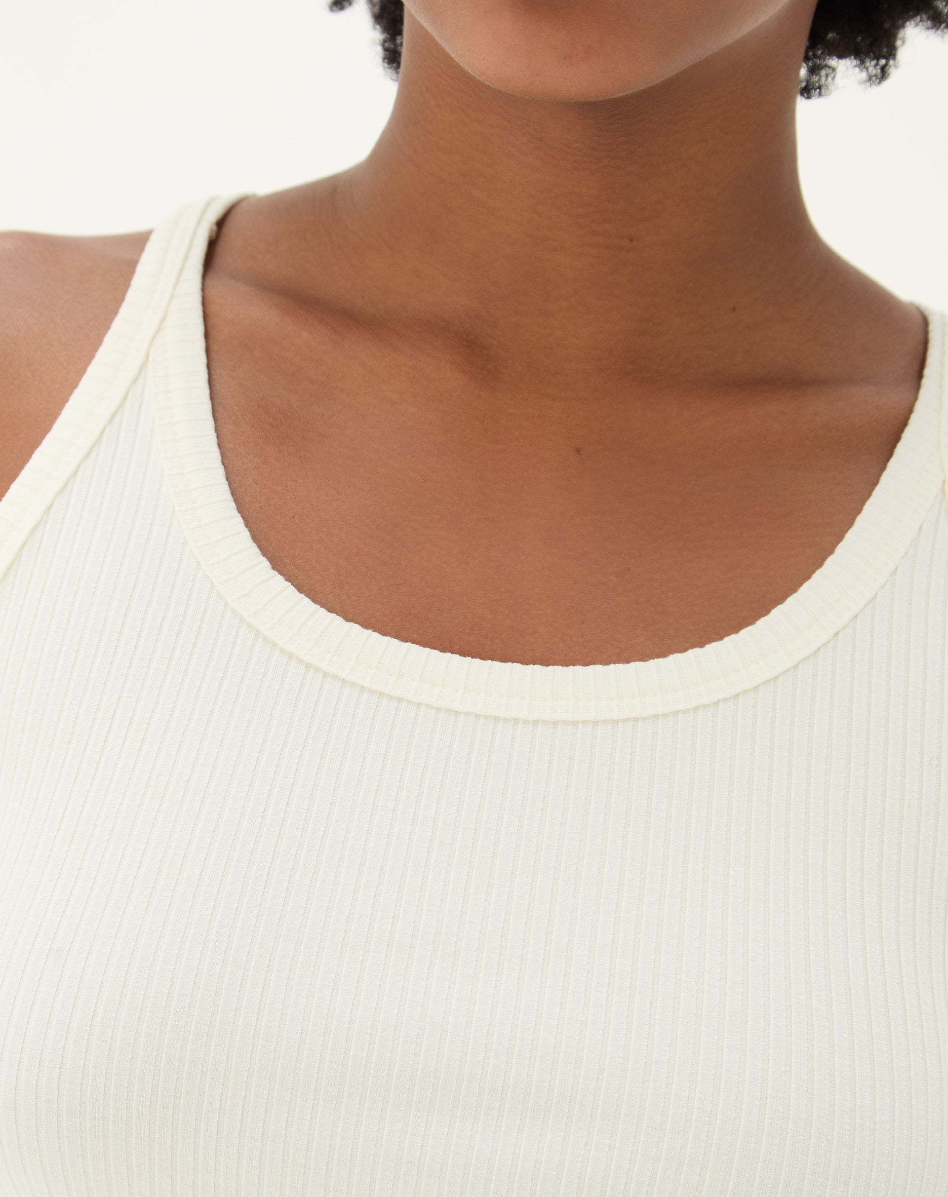 Close-up do decote U da regata de malha ribana off-white.