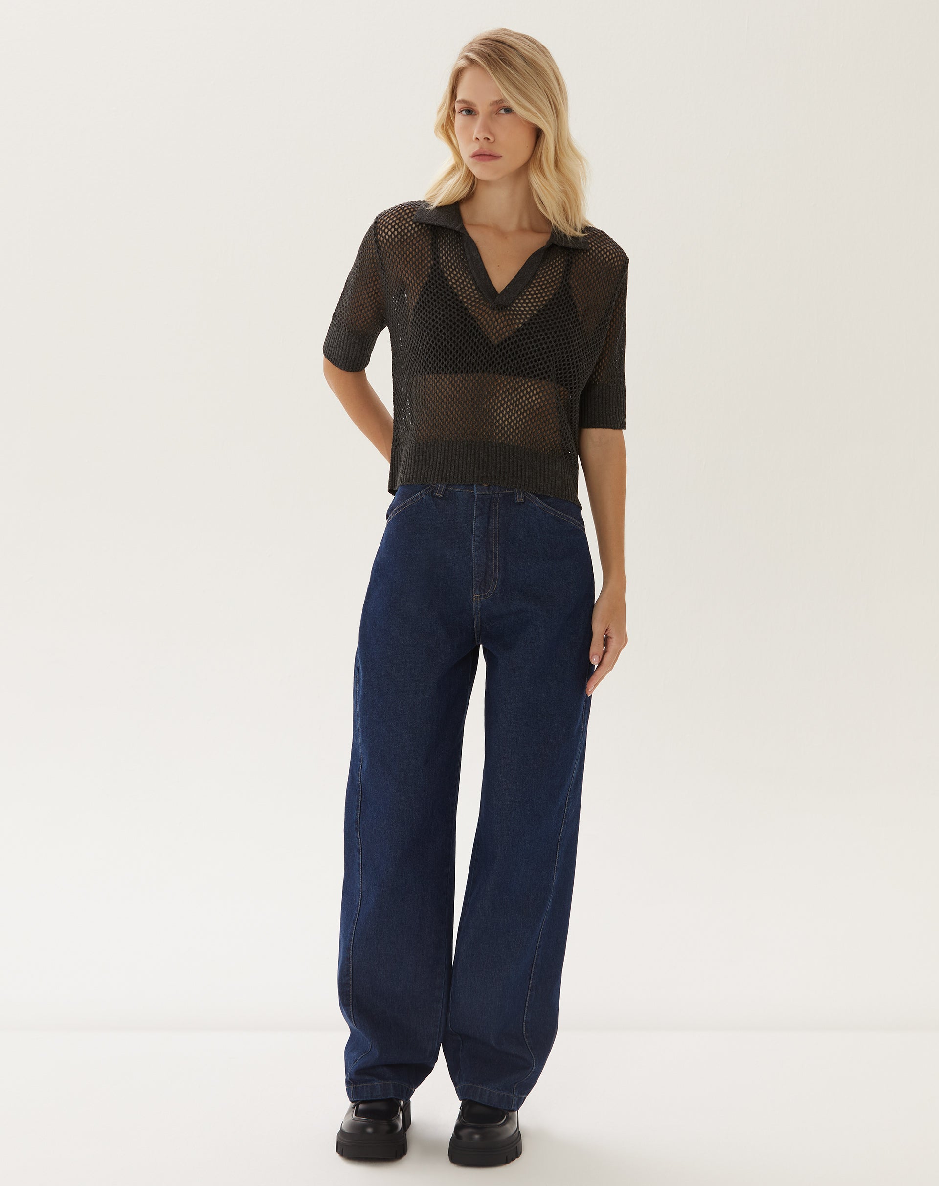 Modelo vestindo blusa polo de tricot telado com calça jeans.