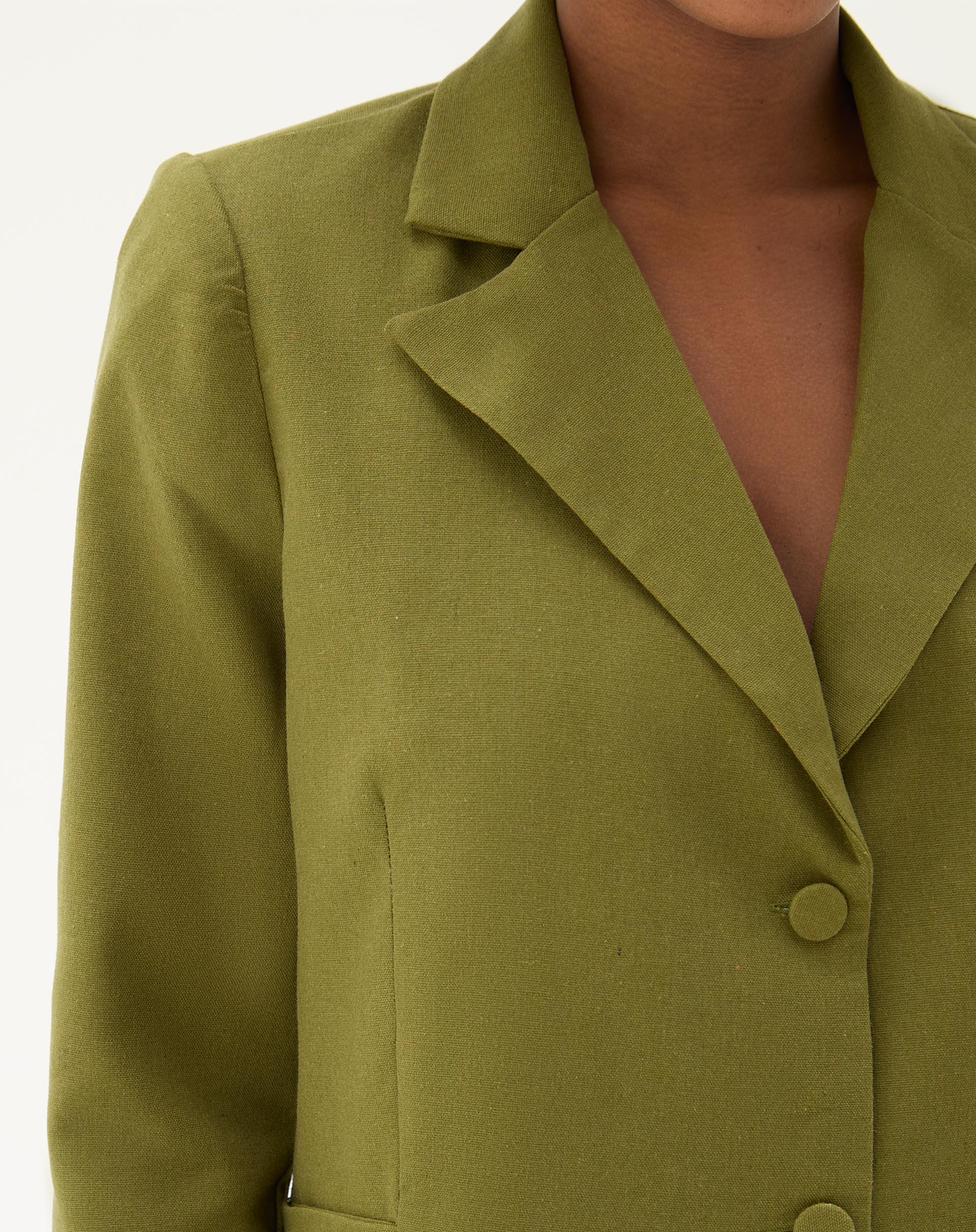 Detalhe da lapela e fechamento do blazer verde militar.