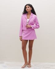 Blazer cropped rosa com lapelas clássicas e fechamento transpassado, visto de frente.