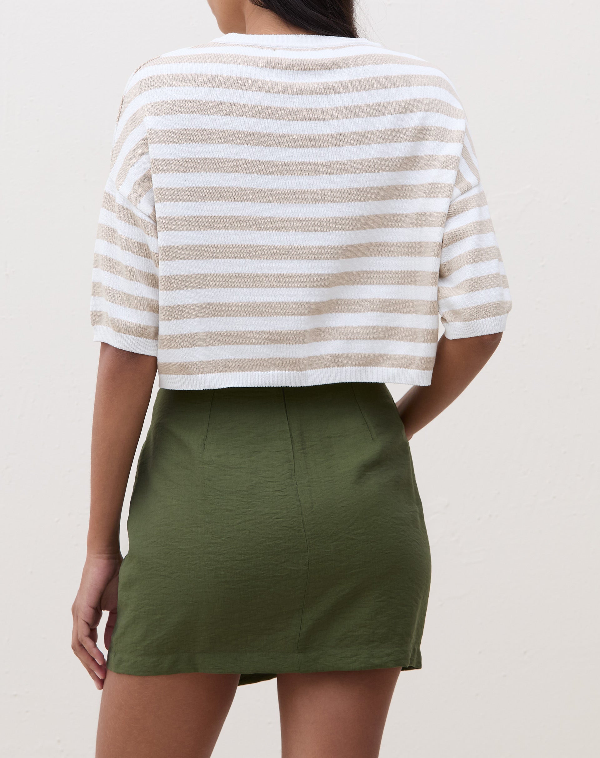 Modelo vestindo saia curta transpassada verde militar com blusa preta.