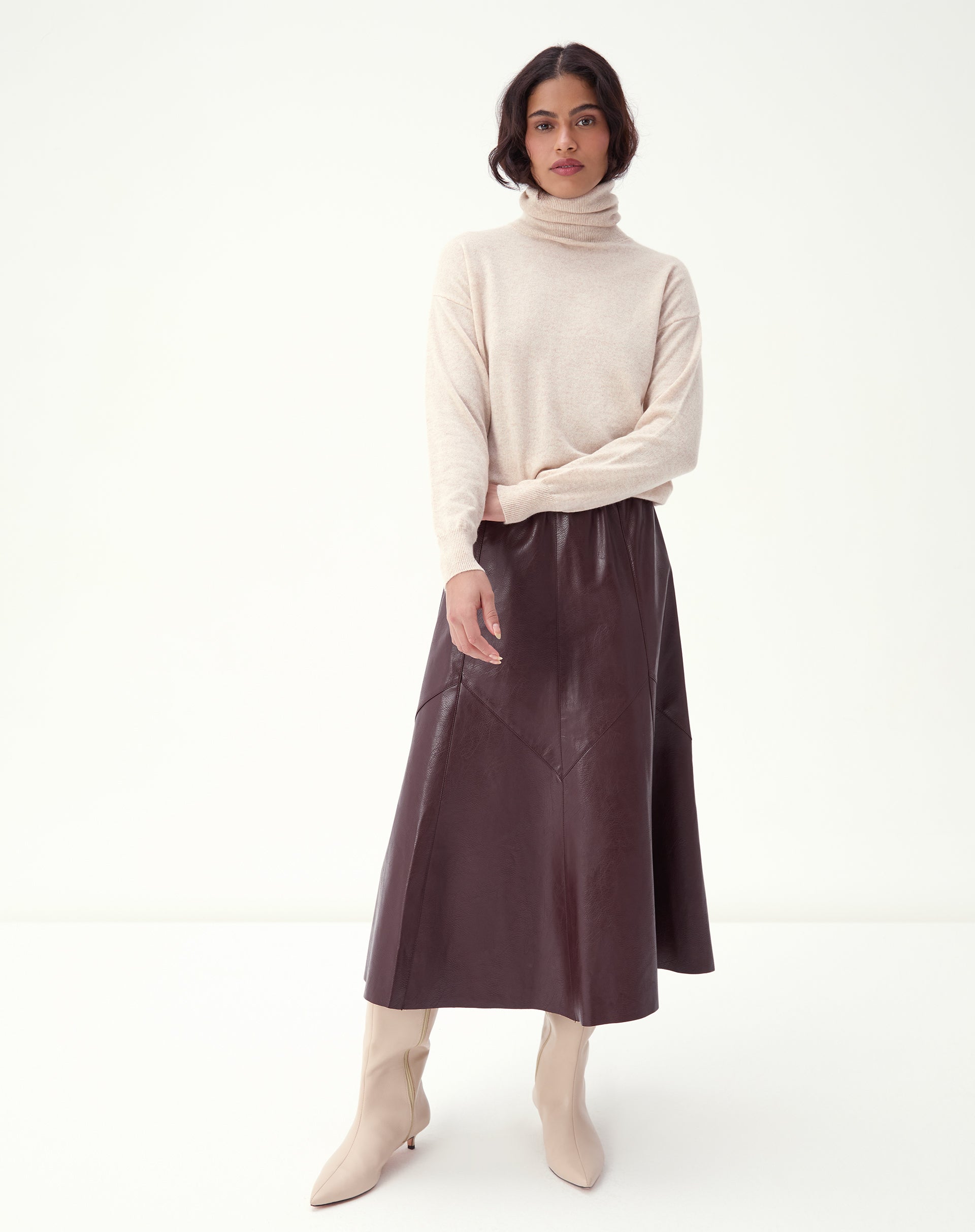 Produto em fundo branco: saia midi Statement burgundy em poliuretano, destaque para o corte em painéis e o comprimento midi