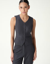 Vista frontal em modelo do colete slim alfaiataria cinza feminino com decote V e botões forrados - colete sem mangas e tecido plano.