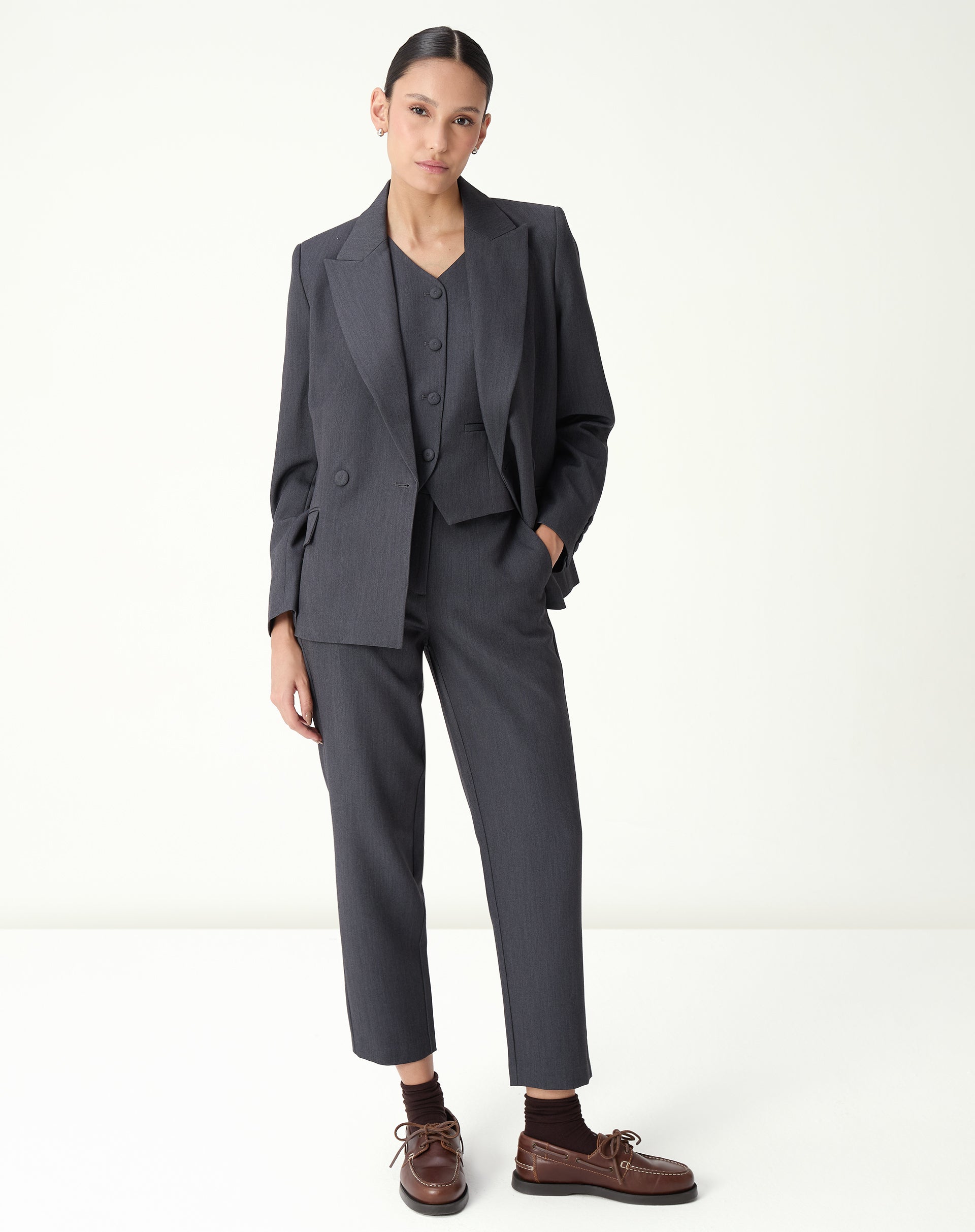 Conjunto de alfaiataria: modelo veste blazer sobre colete slim cinza, formando um look profissional.