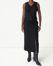 Saia midi preta alfaiataria vista frontal em modelo, corte reto com fenda lateral discreta e colete combinando.