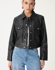 Visão frontal em modelo destacando os dois bolsos de aba com botões prateados e o corte reto da jaqueta preta