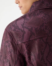 Visual completo com modelo usando jaqueta quadrada cobra em PU vinho e calça combinada, estilo urbano com botas pretas.