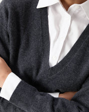 Vista do detalhe frontal do suéter, destacando a textura macia e acabamento impecável sobre camisa branca