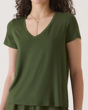 Detalhe do decote em V da camiseta verde, mostrando o tecido de malha.
