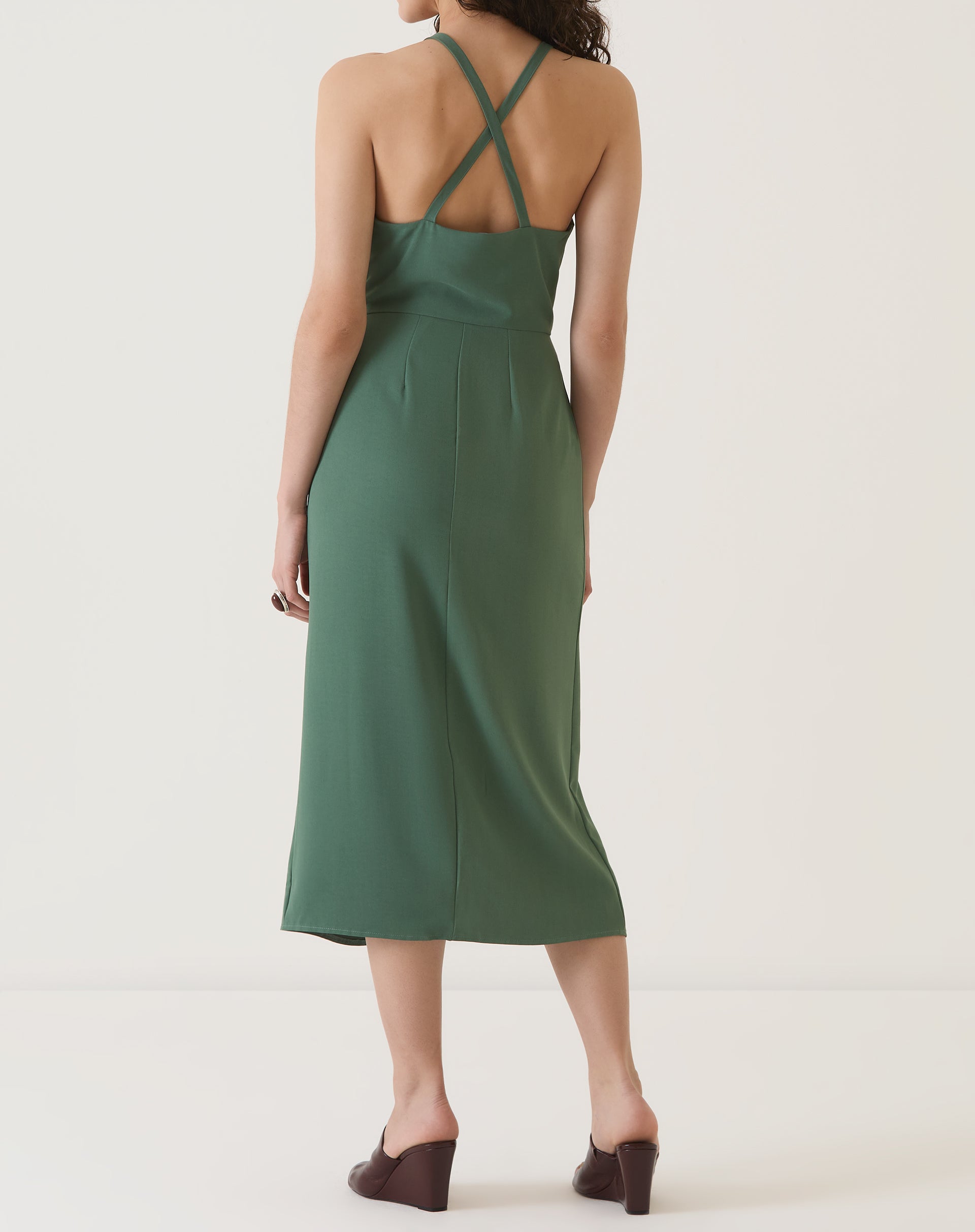 Vista traseira do vestido verde com alças cruzadas e comprimento midi.