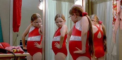 Menina olhando seu corpo no espelho