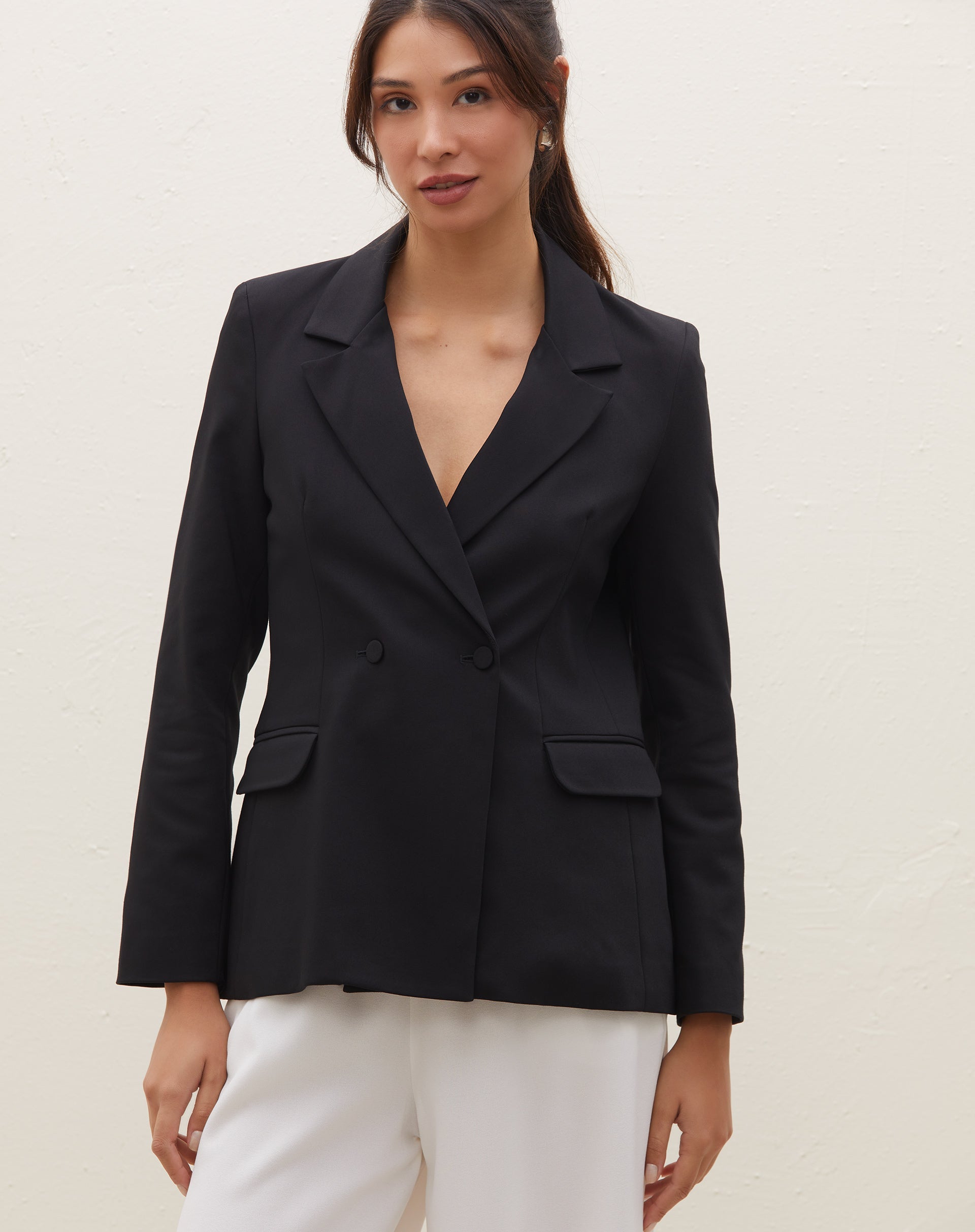 Detalhe do blazer preto mostrando os botões forrados e bolsos com aba.