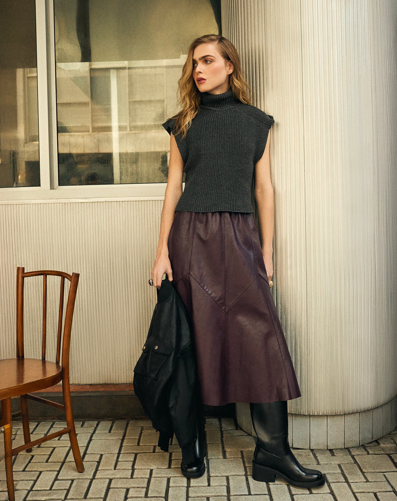 Saia midi burgundy em poliuretano com recortes assimétricos, vista em look urbano com top preto sem mangas e botas pretas - visual statement