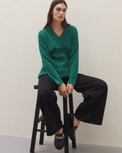 Modelo vestindo mocassim Chunky preto com corrente de metal, combinado com calça preta e blusa verde.