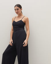 Macacão preto de alcinha com faixa, visto de lado, mostrando o caimento e estilo.