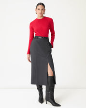 Saia midi alfaiataria cinza com fenda lateral vista frontal em modelo usando suéter vermelho e botas pretas, destacando corte reto e cós médio.