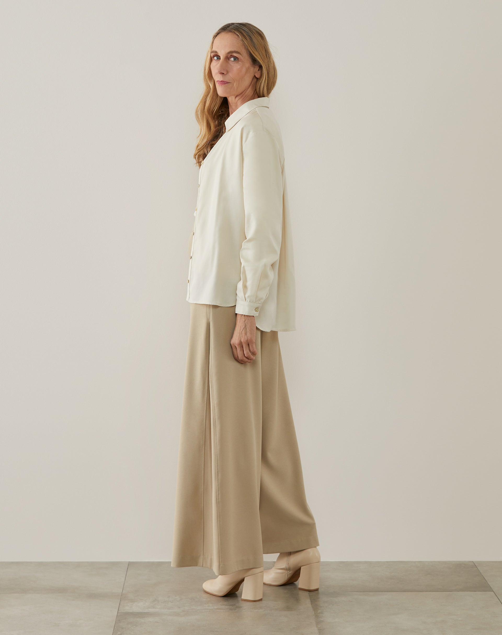 Vista lateral da camisa ampla de Lyocel com calça bege.