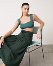Top curto de tricô verde escuro com alças largas, combinado com saia midi.