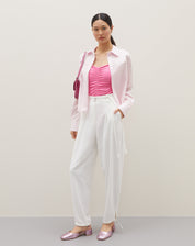 Camisa básica curta em rosa claro, combinada com calça branca e sapatos rosa metálico.