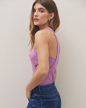 Body rosa neon com decote nadador nas costas e recortes laterais, visto de lado.