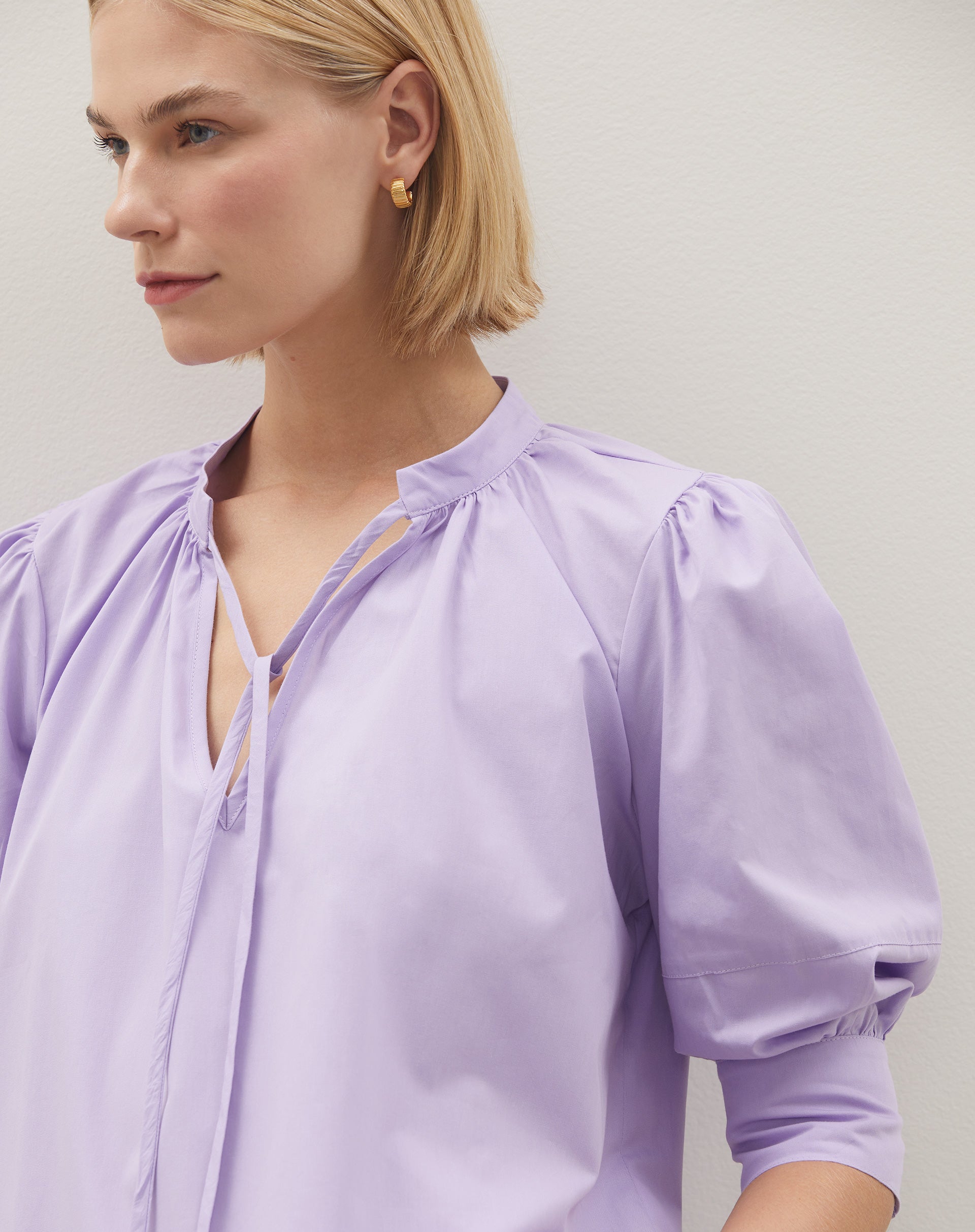 Detalhe das mangas bufantes da blusa lilás.
