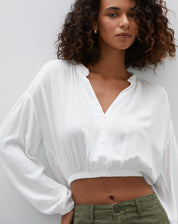 Camisa cropped off-white com decote em V e mangas longas, vista frontal.