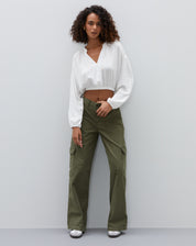 Modelo vestindo camisa cropped off-white com calça verde, vista completa.