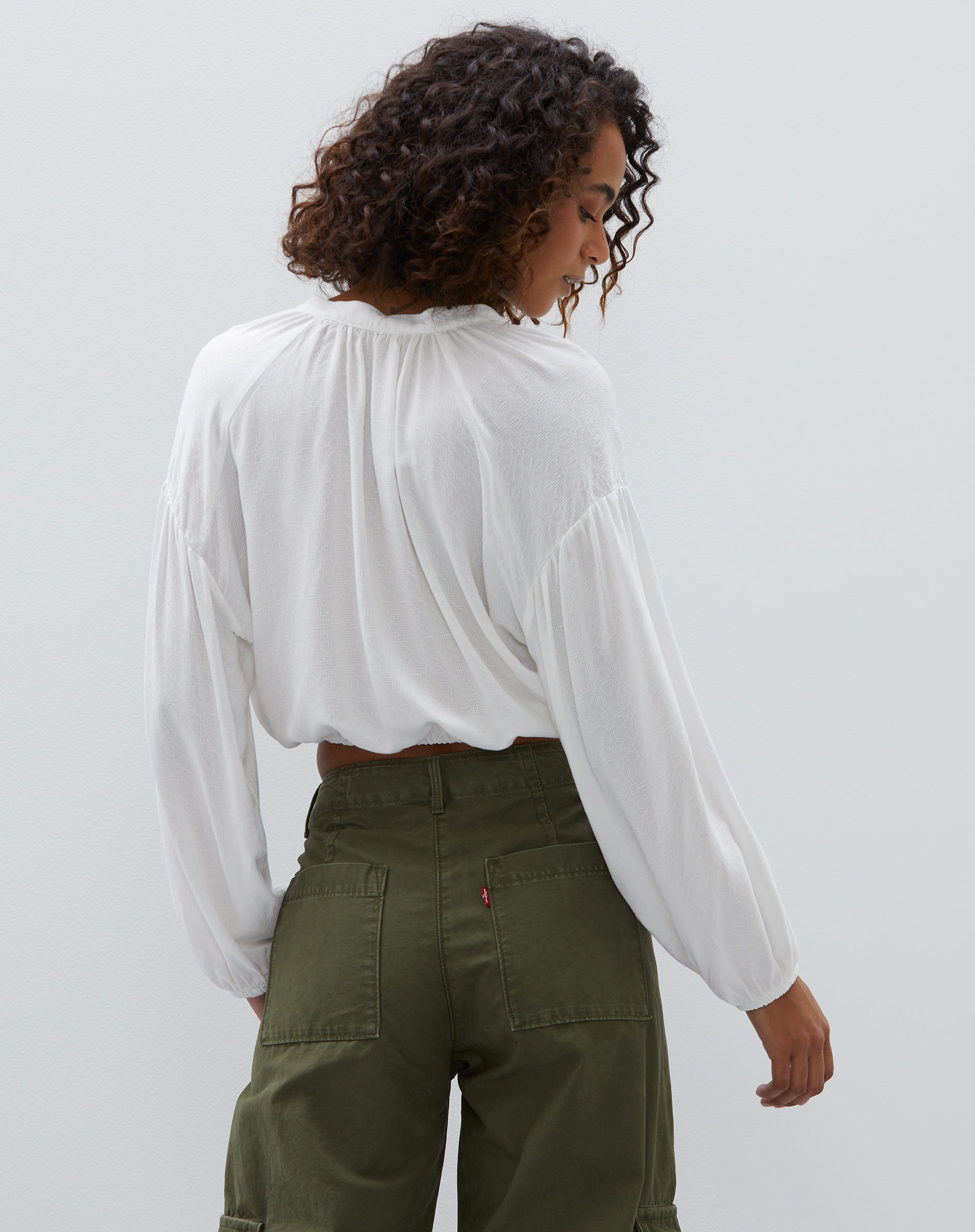 Vista traseira da camisa cropped off-white mostrando o caimento solto.