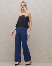 Modelo vestindo blusa sem alça de crepe preta com calça jeans azul, vista frontal.