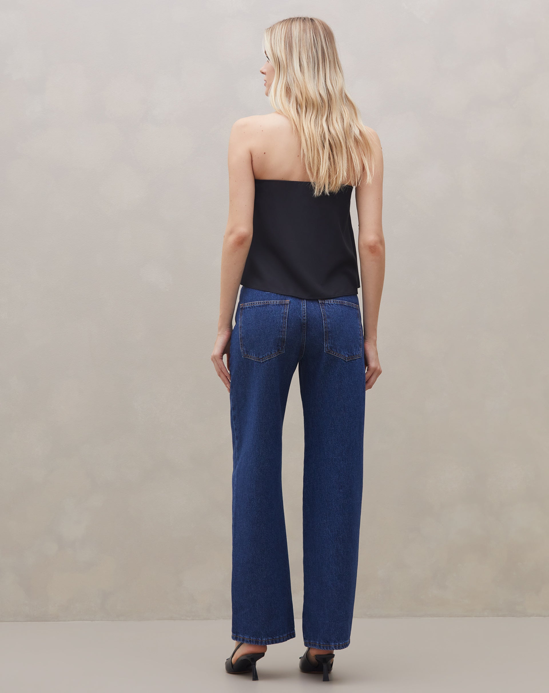 Detalhe do decote da blusa sem alça de crepe preta, com foco no acabamento.