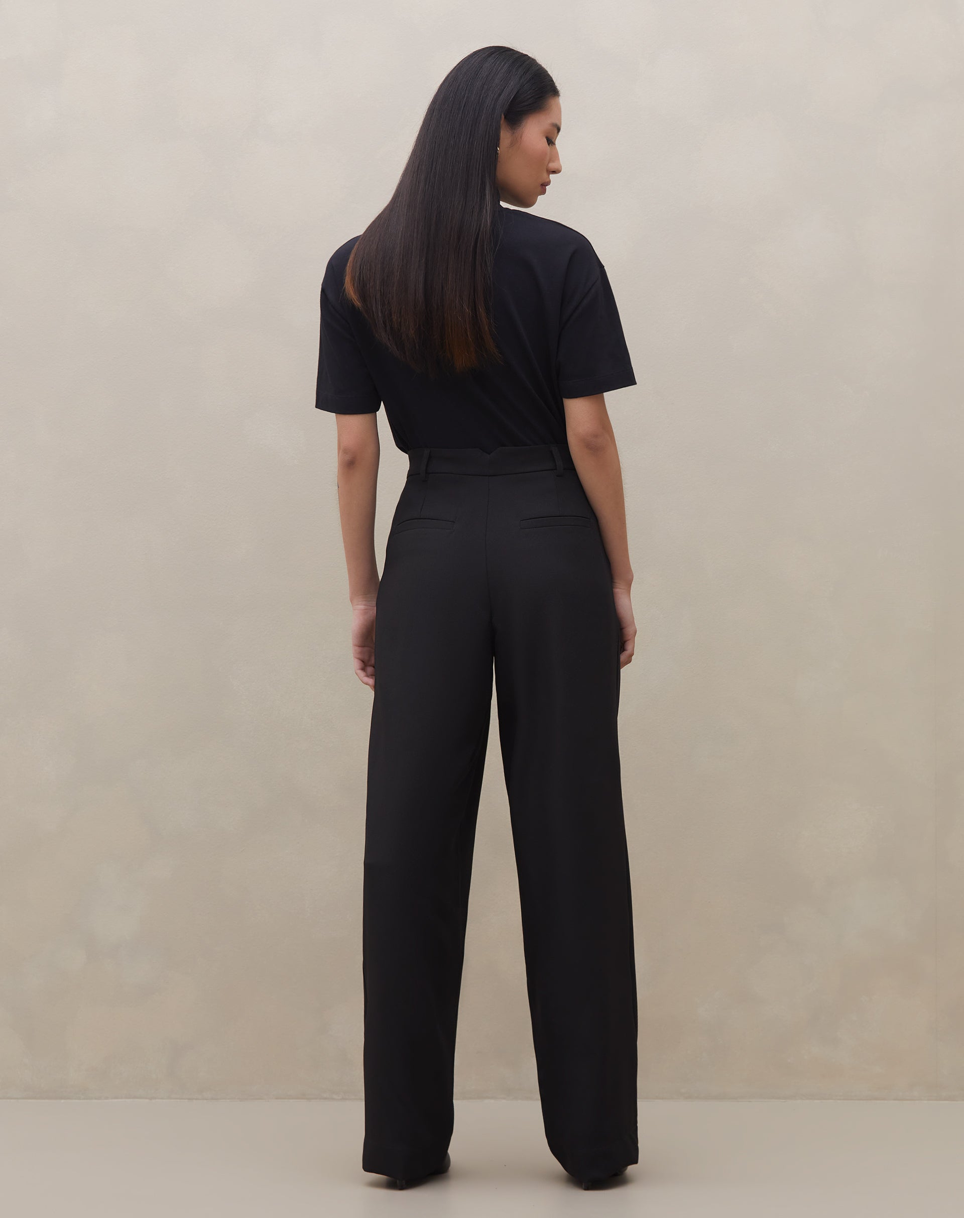 Detalhe do cós limpo e fechamento com botão da calça wide leg preta.
