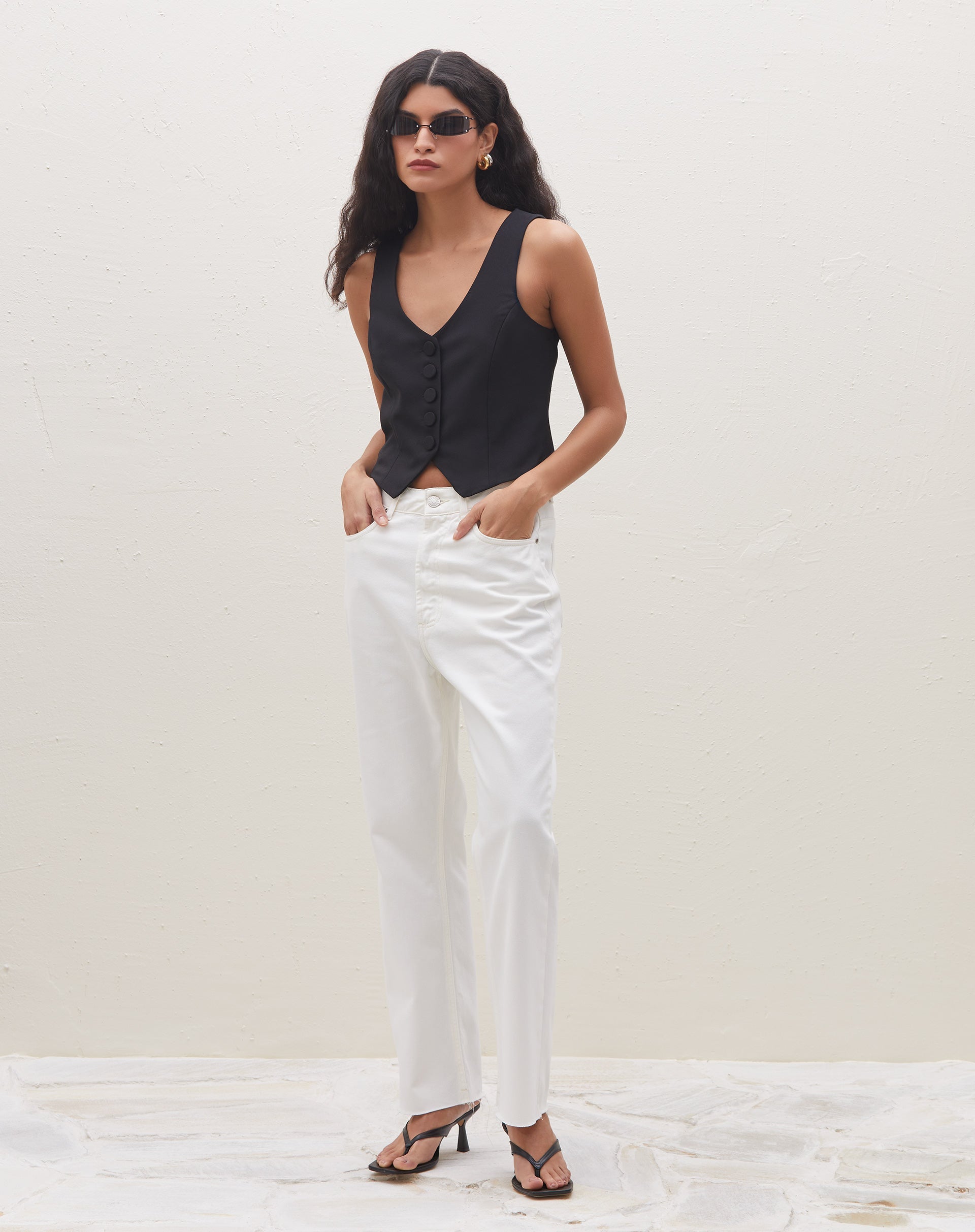 Vista lateral do colete preto de alfaiataria com botões forrados.