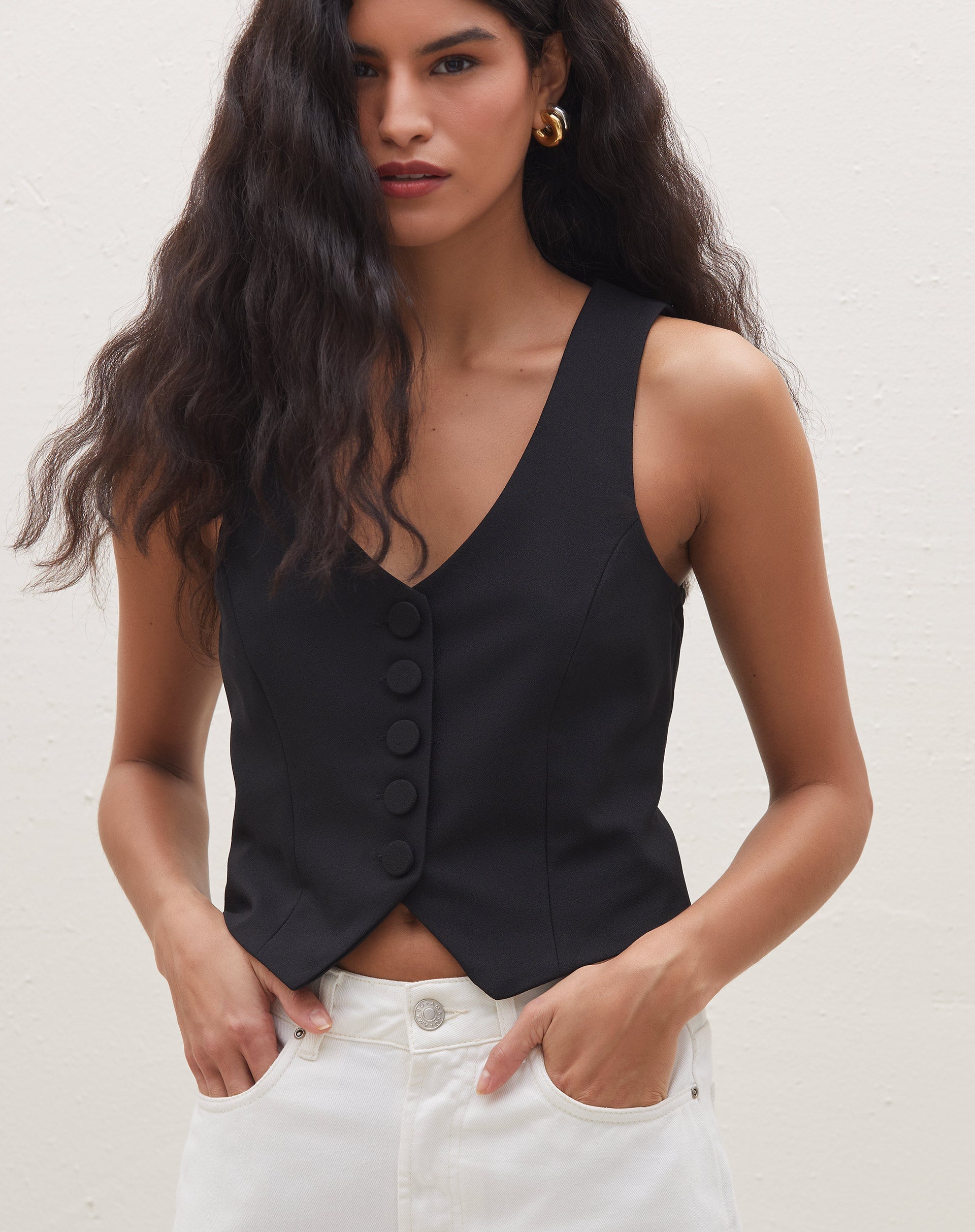 Detalhe do colete preto de alfaiataria mostrando os botões forrados.