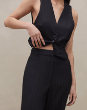 Detalhe da cintura alta e risca de giz da calça preta.