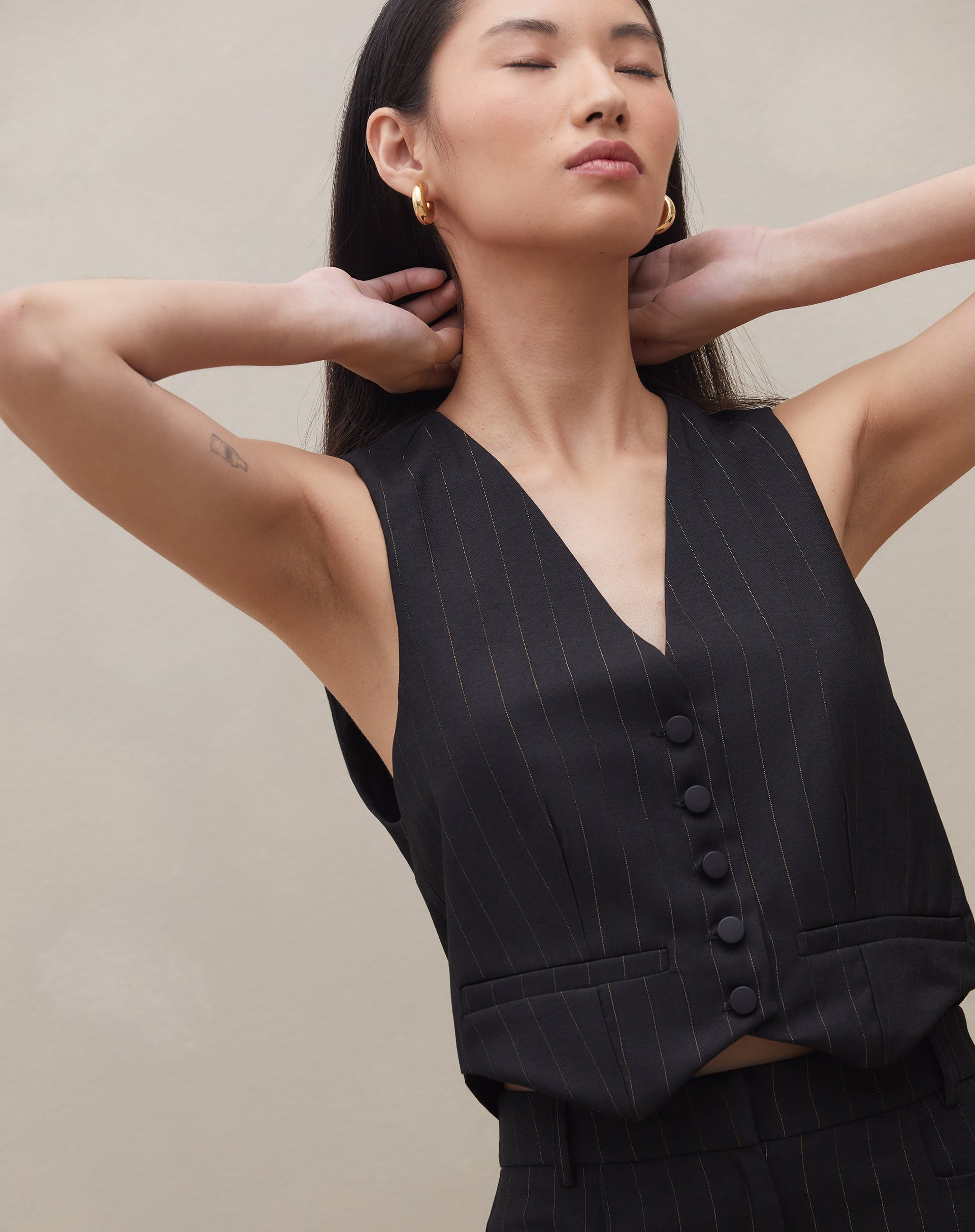 Imagem de um colete de alfaiataria reto preto, com foco nos detalhes do tecido e botões.