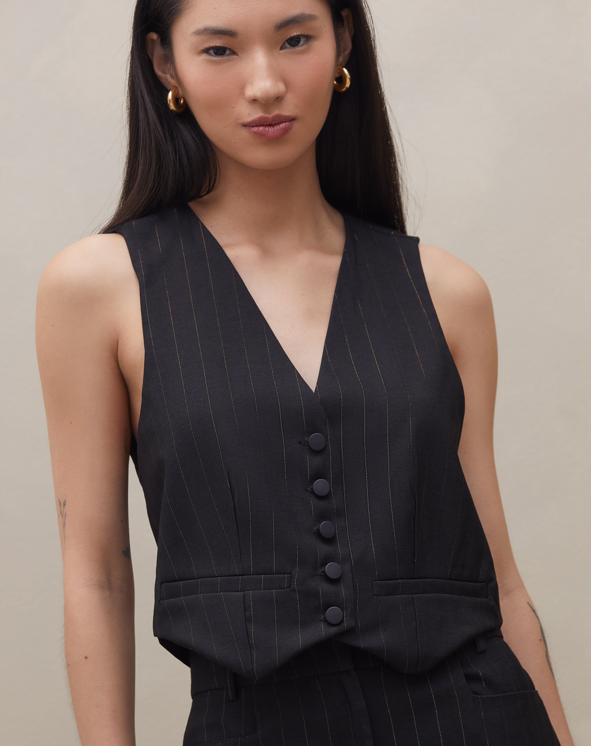 Imagem de um colete de alfaiataria reto preto, com foco no decote e estrutura.