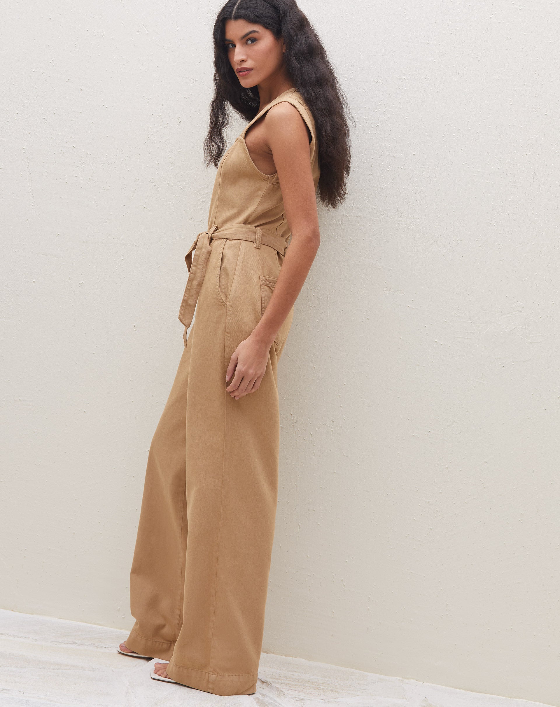 Vista lateral do macacão caramelo mostrando o ajuste na cintura e os bolsos laterais.