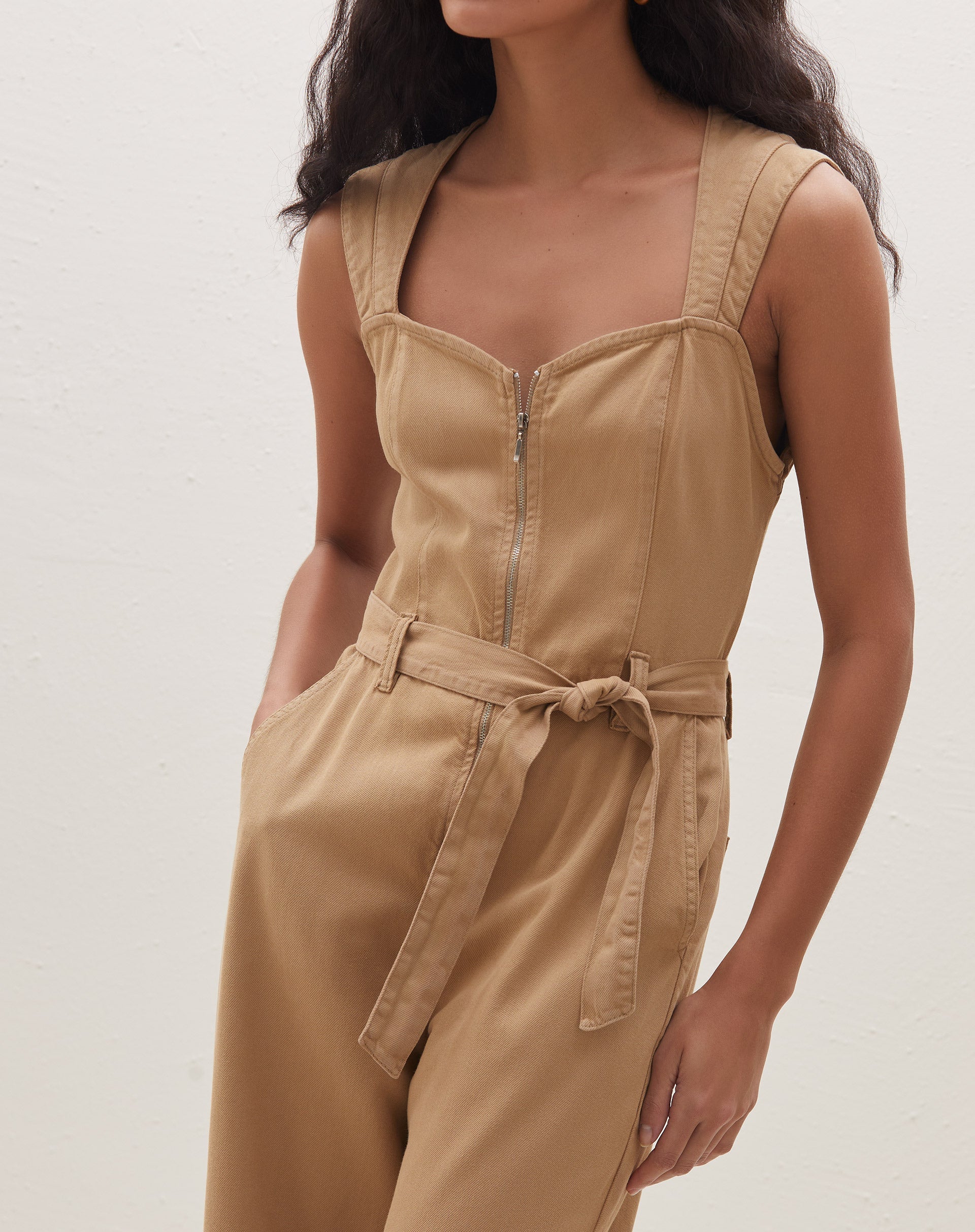 Imagem traseira do macacão caramelo destacando os bolsos traseiros.