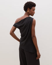 Blusa assimétrica de um ombro só em preto, vista traseira.