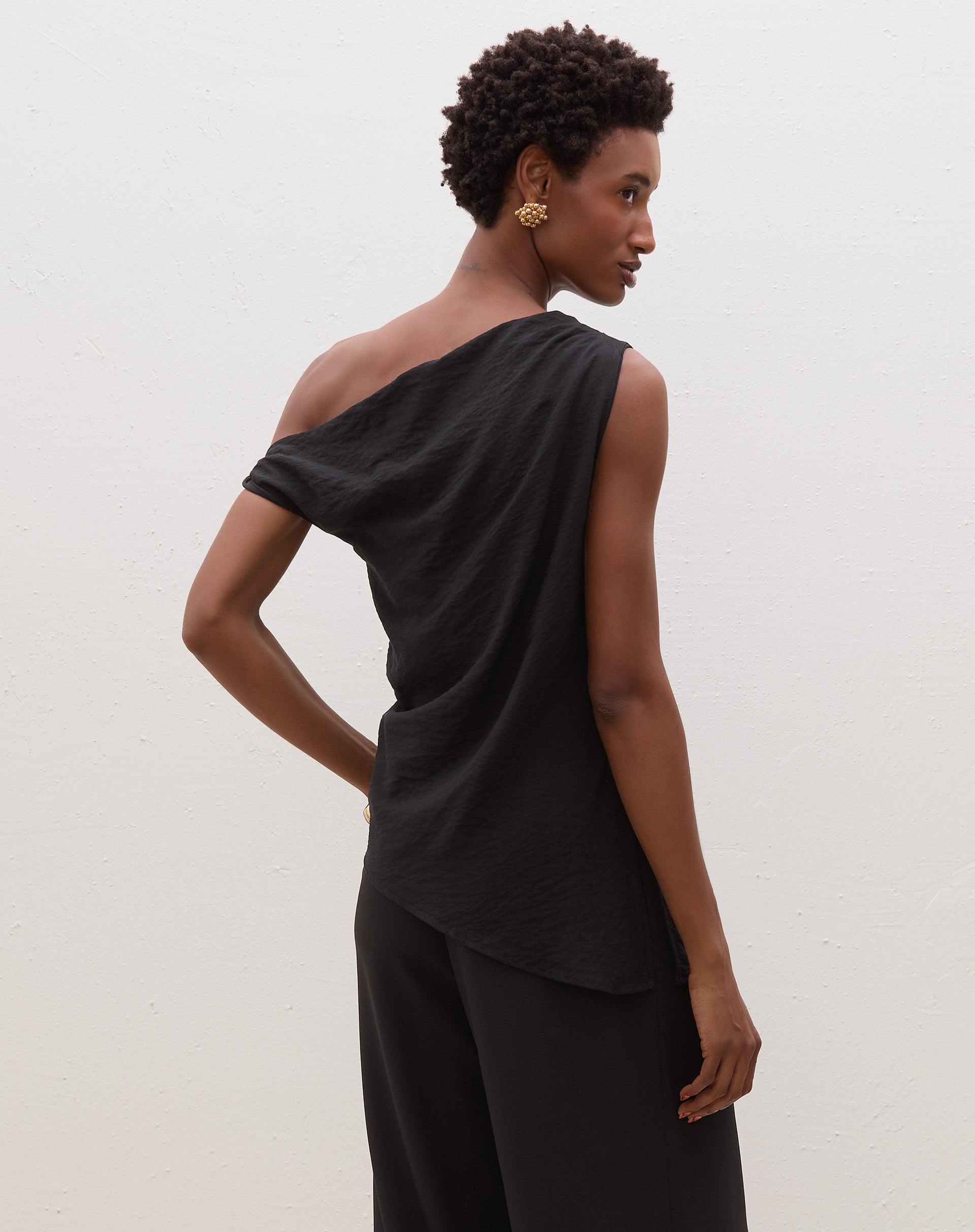 Blusa assimétrica de um ombro só em preto, vista traseira.