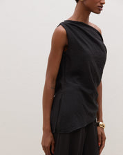 Blusa assimétrica de um ombro só em preto, vista lateral.