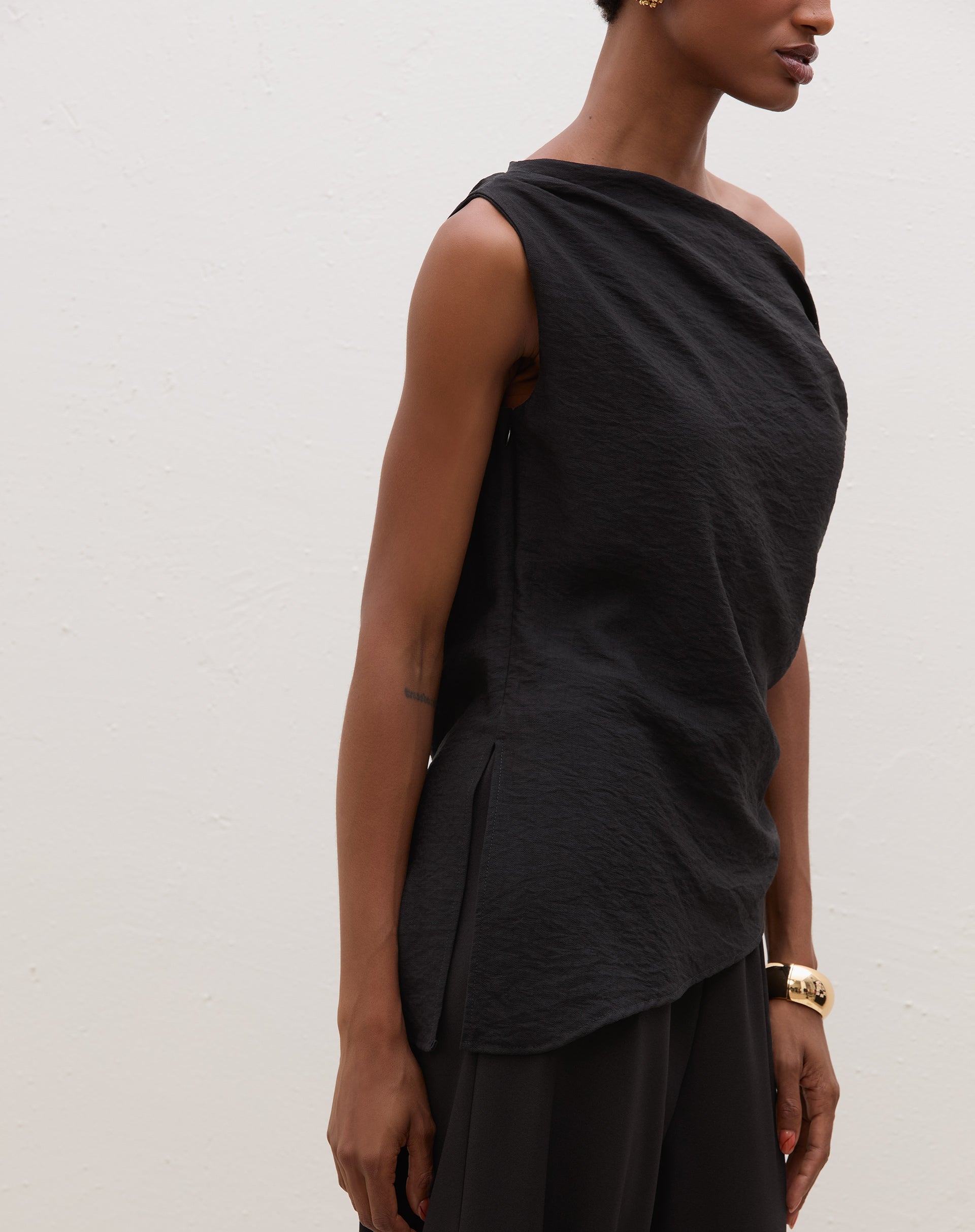 Blusa assimétrica de um ombro só em preto, vista lateral.
