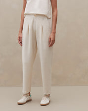 Modelo mostrando detalhes da calça de cintura alta, vista lateral.